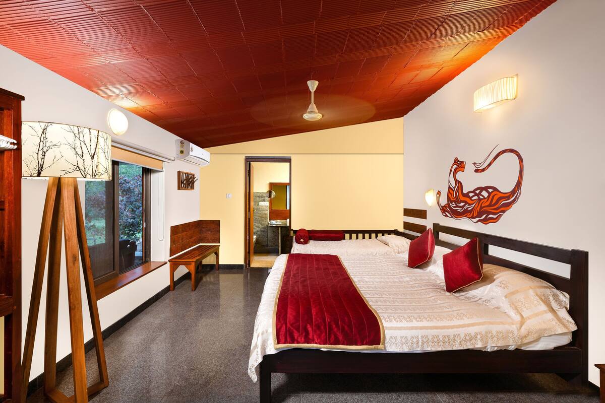 Une chambre avec un plafond en bois, un lit avec une literie rouge et blanche, un banc en bois et un tableau représentant un cygne accroché au mur.
