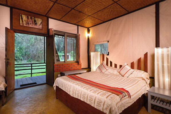 Un dormitorio con una cama grande, una ventana con vistas al exterior, techo de madera y una pequeña mesa.