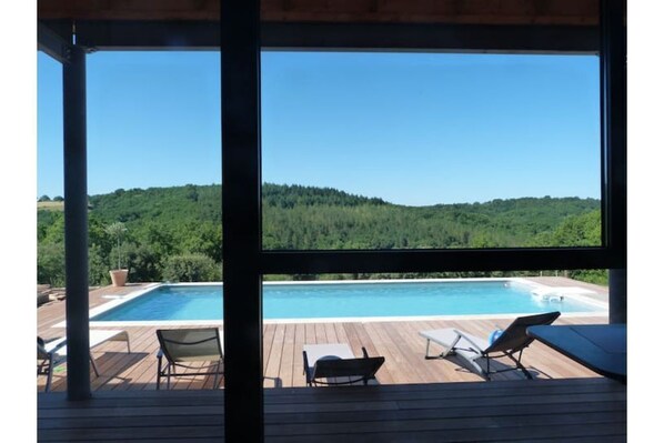 Relax on the deck with a view of the pool and lush hillside.