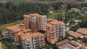 A high-rise residential complex with multiple buildings, a swimming pool, and a golf course in the background. - Toscana Valley Castello Della Valle (Pak Chong)
