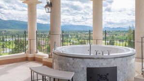 A spa area with a circular hot tub, a bench, and a view of mountains and a river. - Toscana Valley Castello Della Valle (Pak Chong)