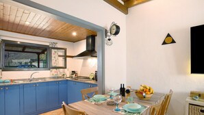 Eine Küche mit blauen Schränken, einem Holztisch und einer Uhr an der Wand.