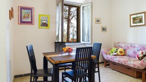 Un comedor con una mesa, sillas y un ventanal con vistas a árboles.