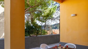 Un balcón con mesa dispuesta para dos, sillas y vistas del paisaje circundante.