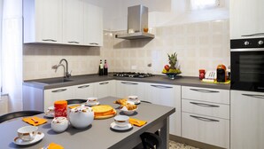 Una cocina moderna con armarios blancos, estufa a gas y una cafetera.