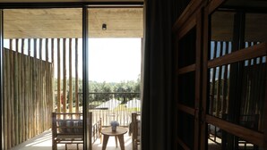 A room with a sliding glass door leading to an outdoor balcony with a wooden table and chairs.