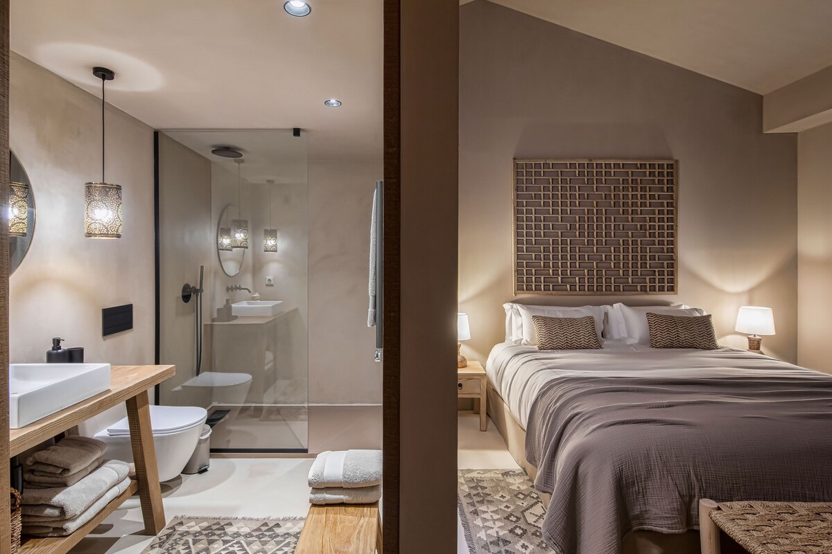 Un baño moderno con cabina de ducha de vidrio, tocador de madera y lavabo blanco.