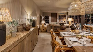 A dining area with wooden tables, wicker lamps, and potted plants.