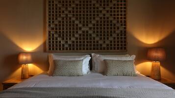 A neatly made bed with patterned pillows, two bedside lamps, and a decorative wall panel above.