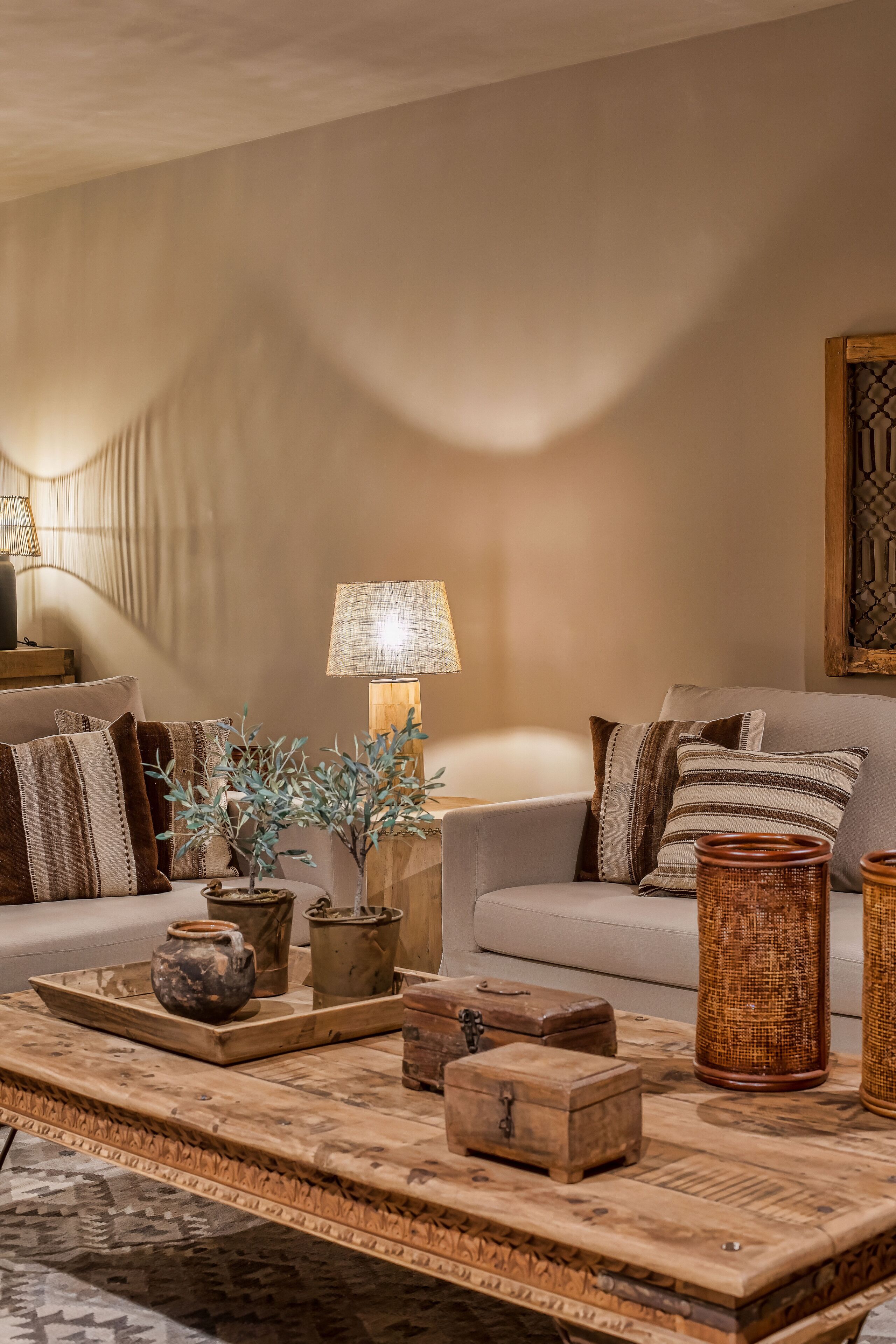 Una sala de estar acogedora con un sofá, cojines, una mesa de centro y objetos decorativos.