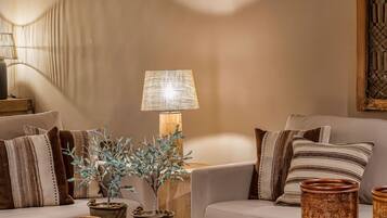 Una sala de estar acogedora con un sofá, cojines, una mesa de centro y objetos decorativos.