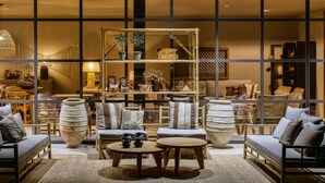 A cozy interior with a sofa set, a wooden coffee table, and a shelving unit displaying various decorative items.