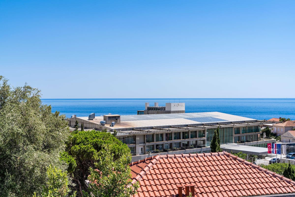 A coastal building with a flat roof, large windows, and a view of the sea.
