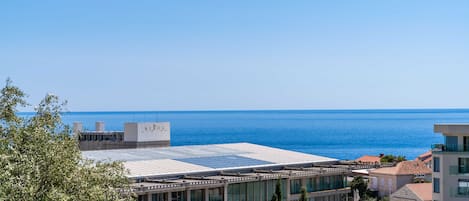 Ein modernes Hotel mit Glasfassade, einer Dachterrasse und Meerblick.