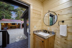 A wooden cabin bathroom with a granite countertop sink, a mirror, and a towel hanging on the wall.