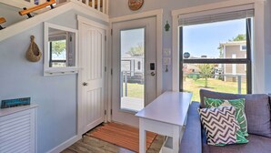 A cozy interior with a white door, a small table, and a gray sofa with patterned cushions. - Upscale Tiny Home - Boho-Chic Austin Getaway! (Austin)