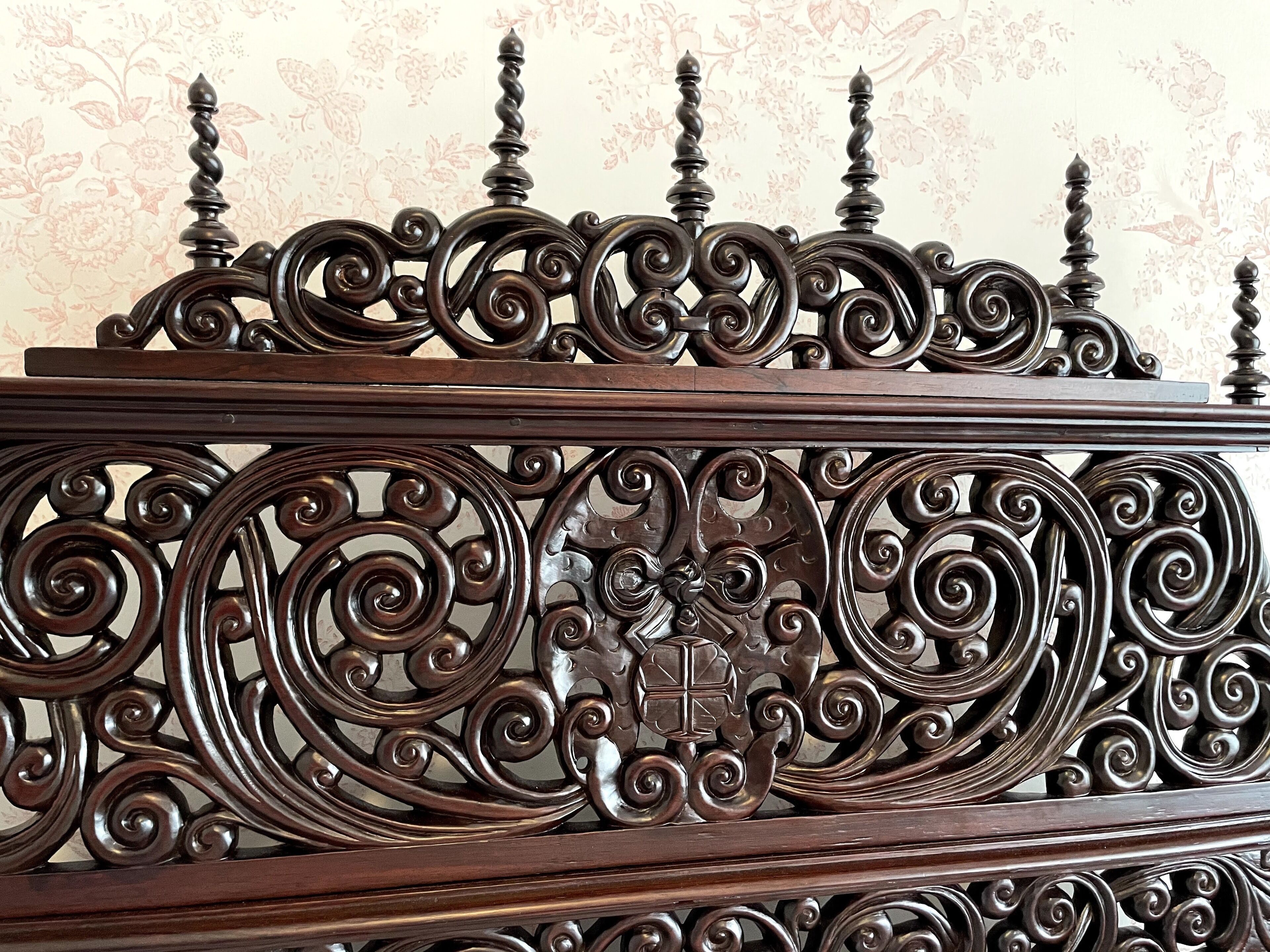 A detailed wrought iron railing with intricate scrollwork and a central emblem.