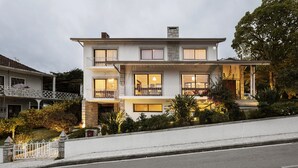Een woonhuis met twee verdiepingen, een balkon op de tweede etage, een overdekte veranda en een verzorgde tuin.
