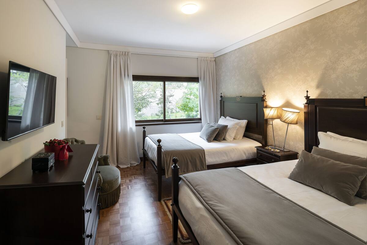 Een hotelkamer met twee bedden, een televisie, een bureau en een raam met gordijnen.