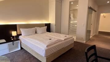 A hotel room with a bed, bedside table, lamp, and a chair.