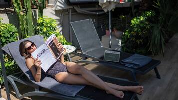 A person lying on a sun lounger reading a magazine.