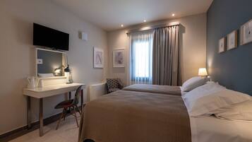 Une chambre d’hôtel avec deux lits, un bureau doté d’un téléviseur à écran plat, une chaise et une fenêtre avec des rideaux.