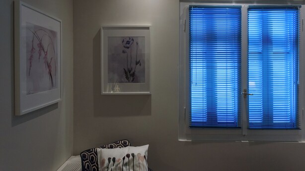 A room with two framed artworks on the wall, a door with a window, and a patterned pillow on the bed. - Thalias Quarters - Kalamata Mediterranean Suites & Villas (Kalamata)