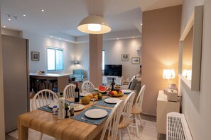 Un comedor moderno con una mesa de madera, sillas blancas y una isla central con taburetes de bar.