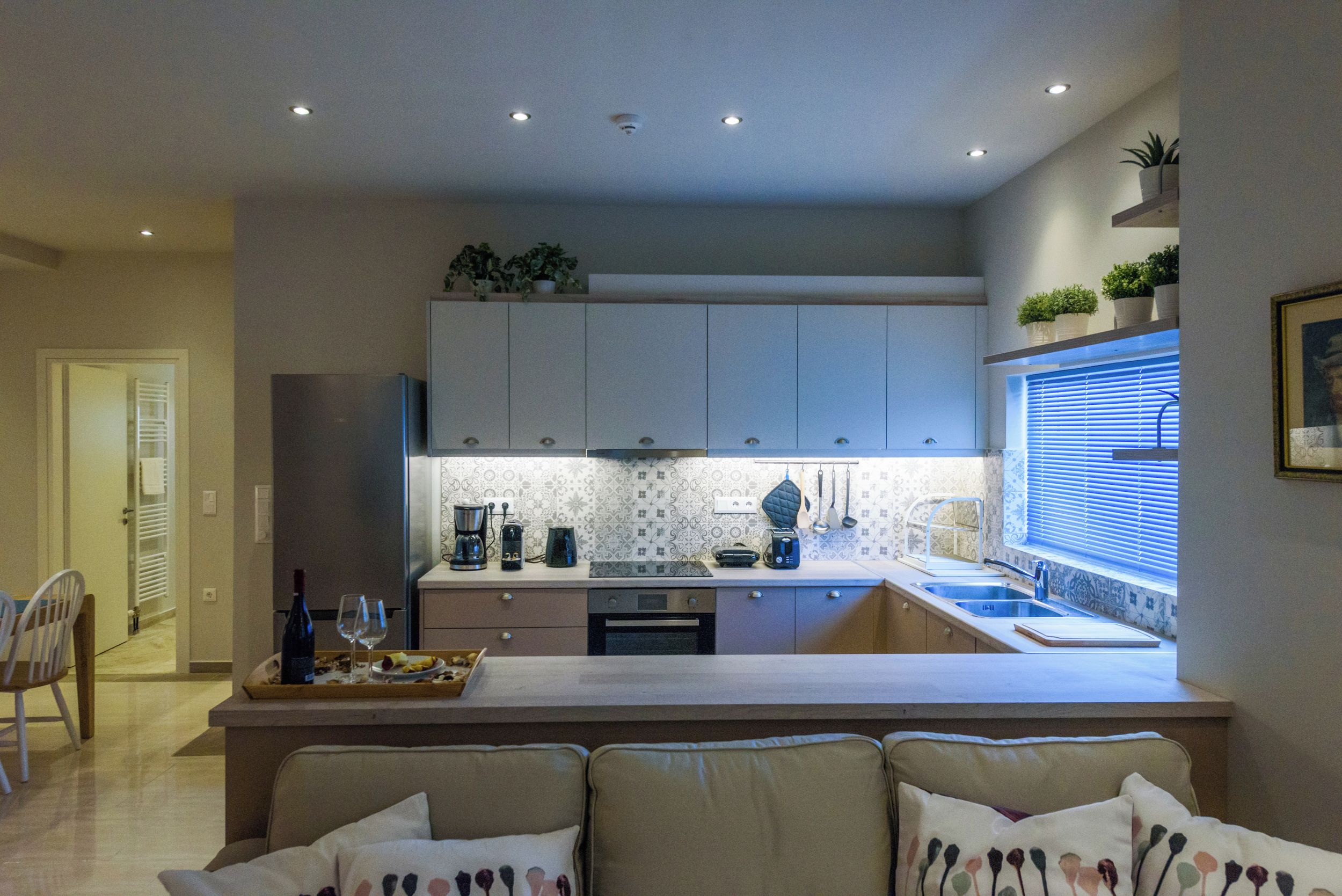 A modern kitchen with white cabinets, a central island, and a window with blinds.
