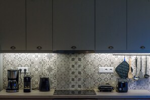 A kitchen with a coffee maker, toaster, and electric kettle on the counter. - Thalias Quarters - Kalamata Mediterranean Suites & Villas (Kalamata)