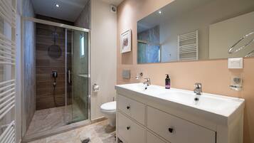 A modern bathroom with a glass-enclosed shower, a white sink, and a large mirror.