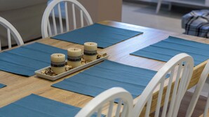 A dining table set with blue placemats, white chairs, and candles. - Thalias Quarters - Kalamata Mediterranean Suites & Villas (Kalamata)
