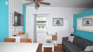 A living room with a white TV, grey sofa, and a ceiling fan. - Heart of South Beach ¤ 2 min Plage ¤ Ocean Drive (Miami Beach)
