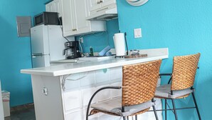 A kitchen with a central island, white cabinets, a microwave, and two wicker chairs. - Heart of South Beach ¤ 2 min Plage ¤ Ocean Drive (Miami Beach)