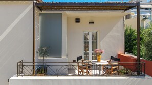 A balcony with a table and chairs, a potted plant, and a window.