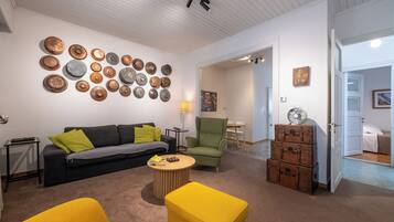 A living room with a sofa, two yellow armchairs, a coffee table, and a wall of decorative plates.