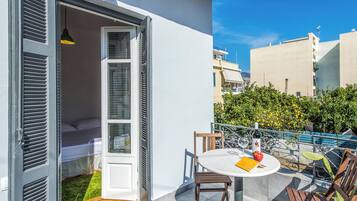 Ein Balkon mit einem Bett, einem Tisch mit einer Flasche und einem Apfel, sowie einem Stuhl.