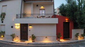 A two-story building with a balcony, potted plants, and a door.