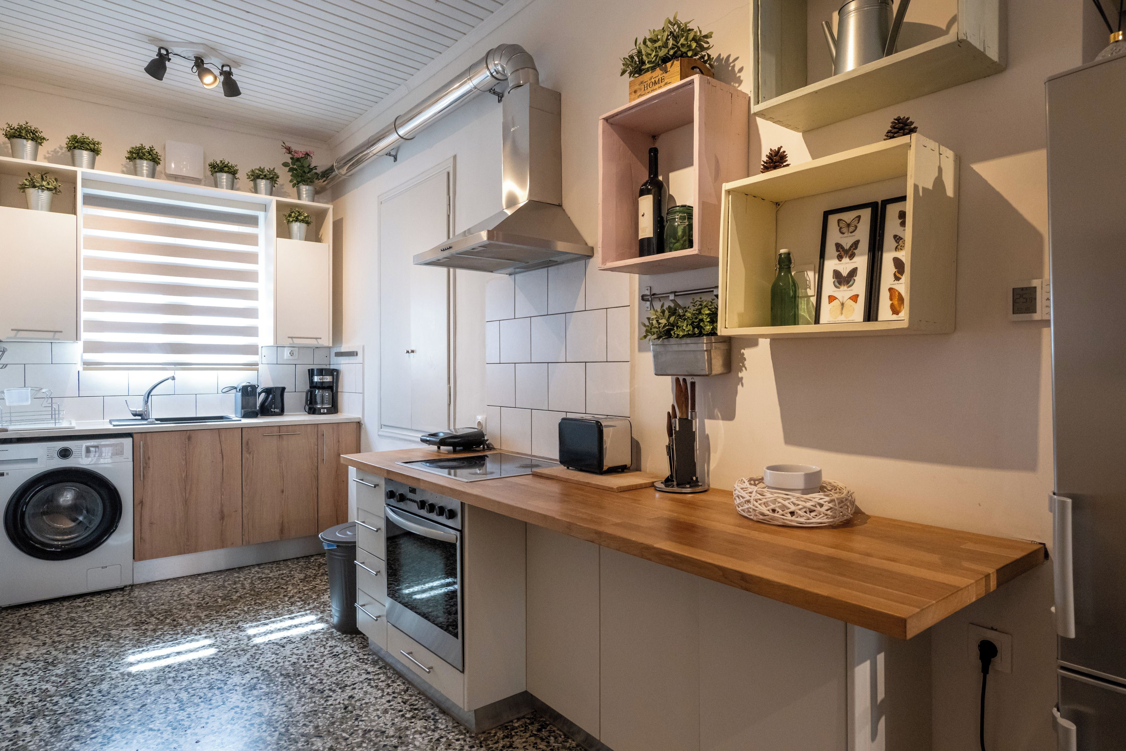 Une cuisine moderne équipée d’un lave-linge, d’un four et d’un plan de travail en bois.