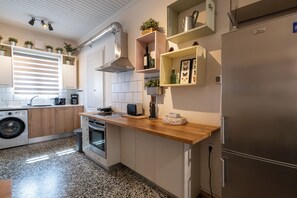 Une cuisine moderne équipée d’un lave-linge intégré, d’un réfrigérateur en acier inoxydable et d’un plan de travail en bois.