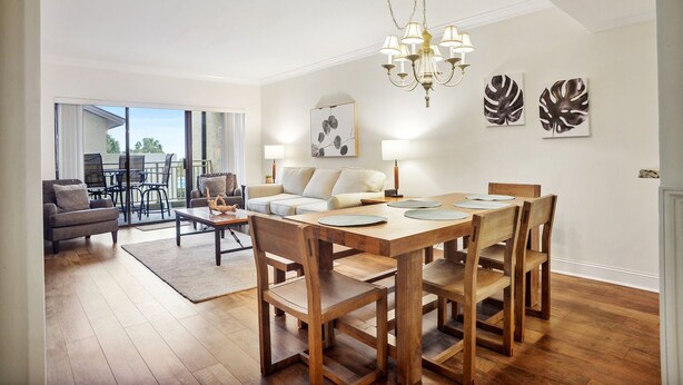 Una sala de estar moderna con una mesa de comedor de madera, un sofá y una araña.