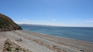 Una playa costera con terreno rocoso y una vista despejada del mar.
