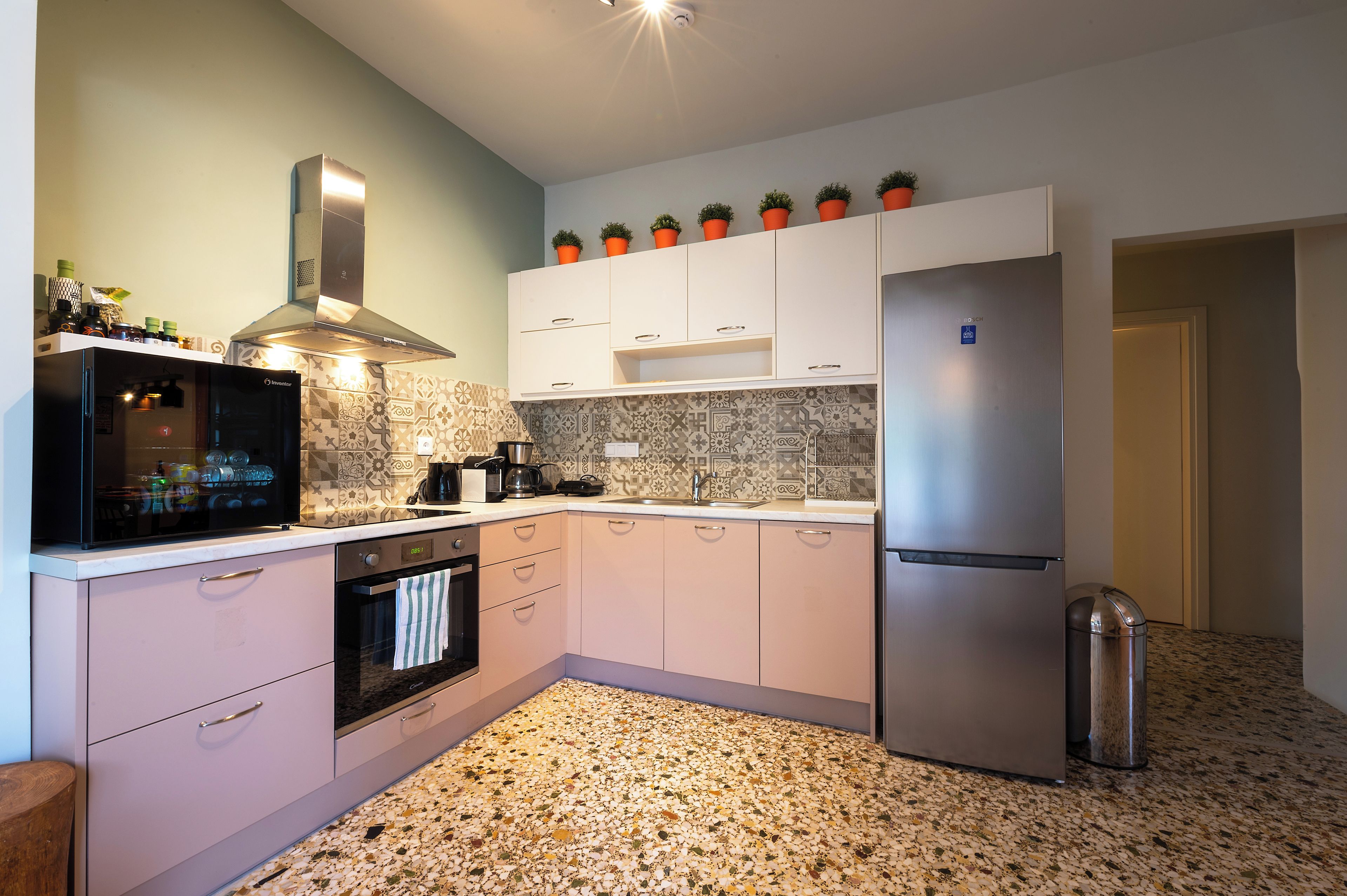 A modern kitchen with white cabinets, a stainless steel refrigerator, and a patterned backsplash.