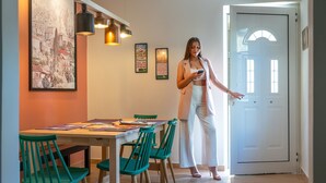 A dining area with a table, chairs, and a person standing by the door. - Tinas Home - Kalamata Mediterranean Suites & Villas (Kalamata)