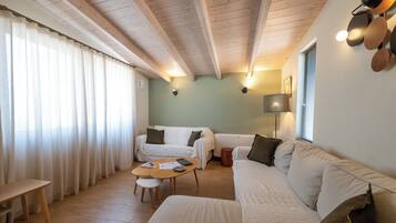 A cozy room with a wooden ceiling, a sofa, a small table, and a window with curtains.