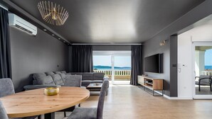 A modern living room with a sofa, dining table, and TV. - Villa Marisa with 51sqm heated, private pool, 5 bedrooms, 4 bathrooms, summer kitchen, views of the Adriatic sea and town Split (Kastel Kambelovac)