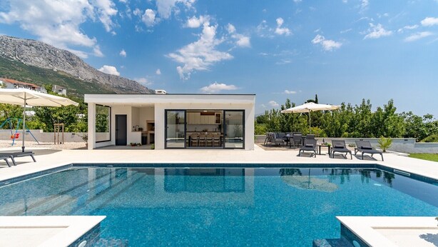 A modern pool area with a clear blue pool, a covered outdoor kitchen, and lounge chairs. - Villa Marisa with 51sqm heated, private pool, 5 bedrooms, 4 bathrooms, summer kitchen, views of the Adriatic sea and town Split (Kastel Kambelovac)