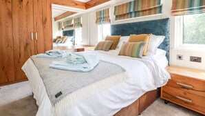 Un dormitorio con una cama grande, un armario de madera y una ventana con cortinas a rayas.
