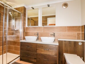 A modern bathroom with a glass-enclosed shower, two sinks, and a vanity with drawers. - Atlantic Lodge (Bude)