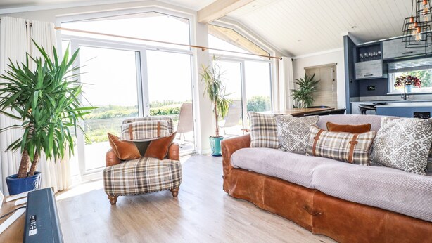 Amplia sala de estar con sofá, sillón y un ventanal con vistas a la vegetación.
